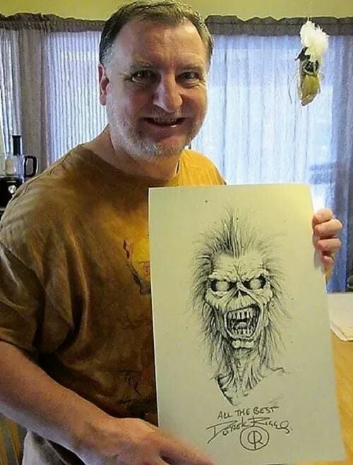 Derek Riggs sosteniendo un dibujo original de Eddie the Head, el personaje que creó para las portadas de Iron Maiden.